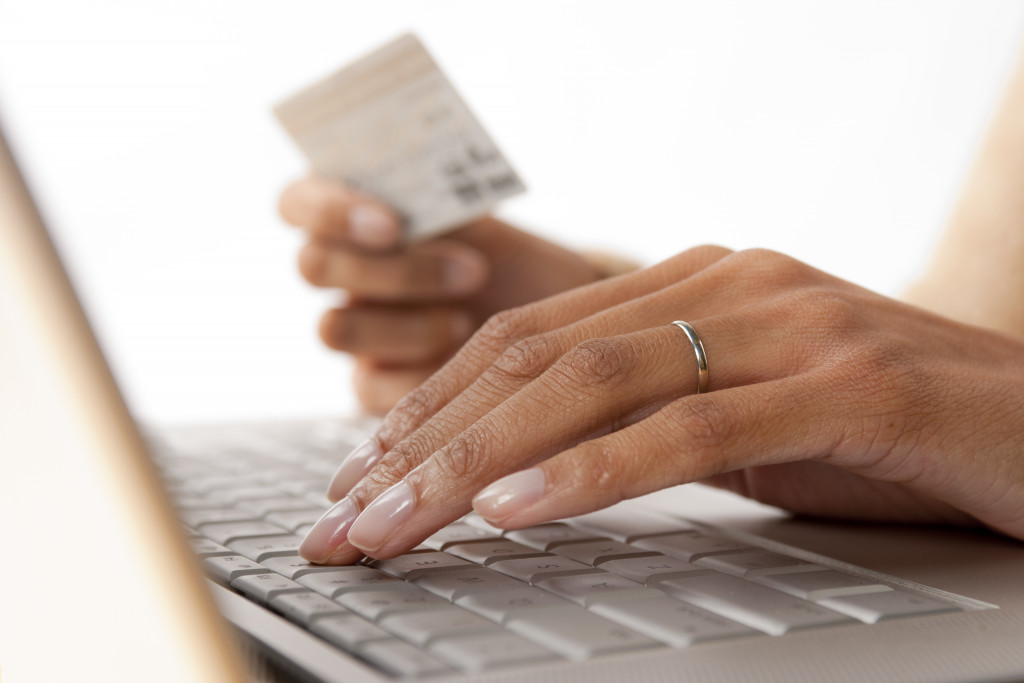 woman using laptop holding card
