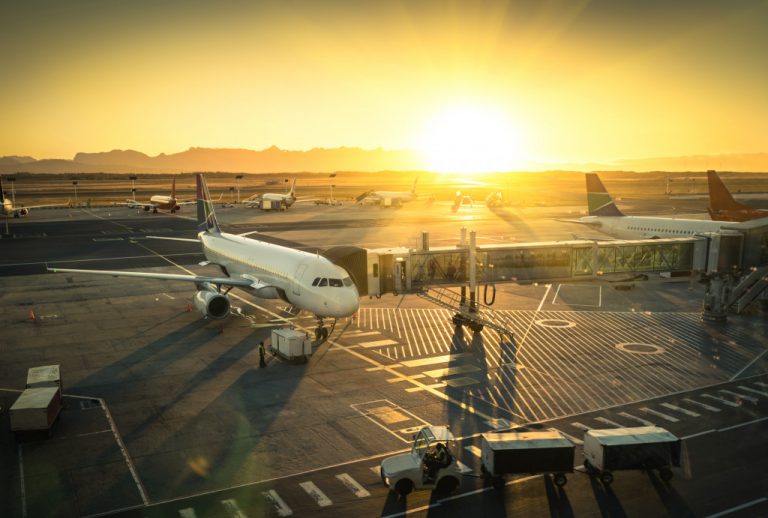 a plane parked with the sun setting in the background