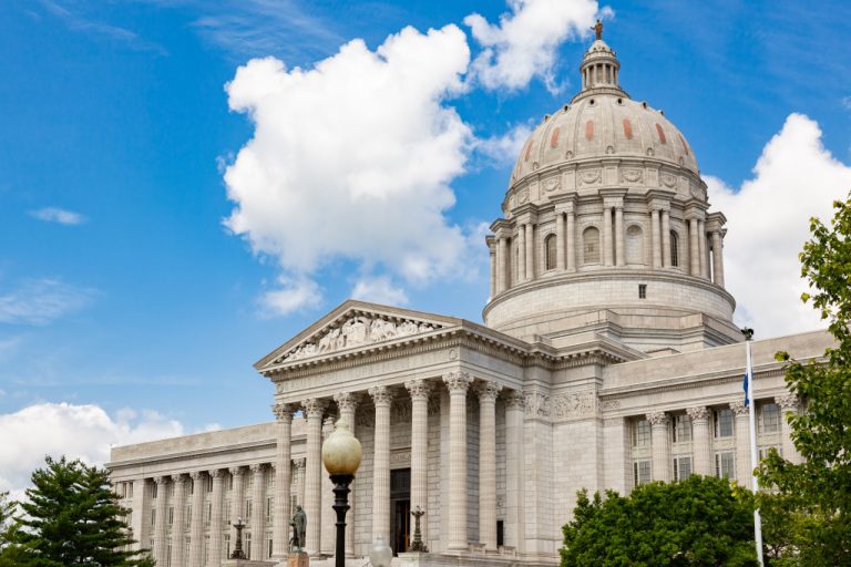 A government building in front of a blue sky with clouds